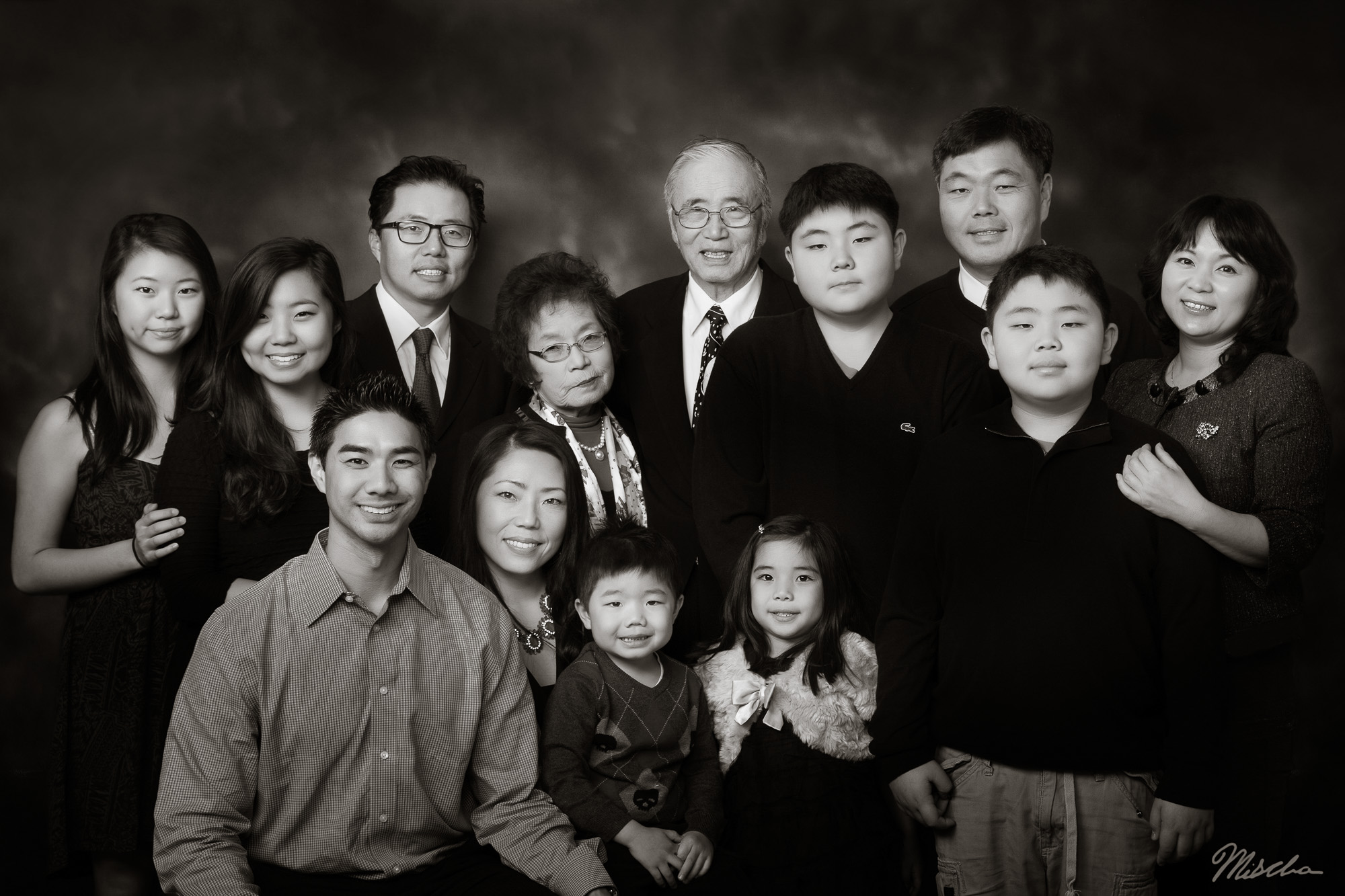 Black and white portrait of a large multi-generational East Asian family with thirteen members.