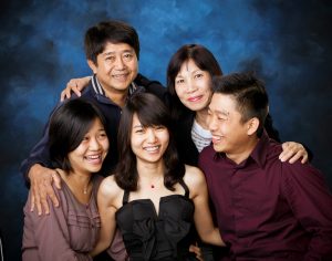 Five people posing together smiling in front of a blue studio backdrop.