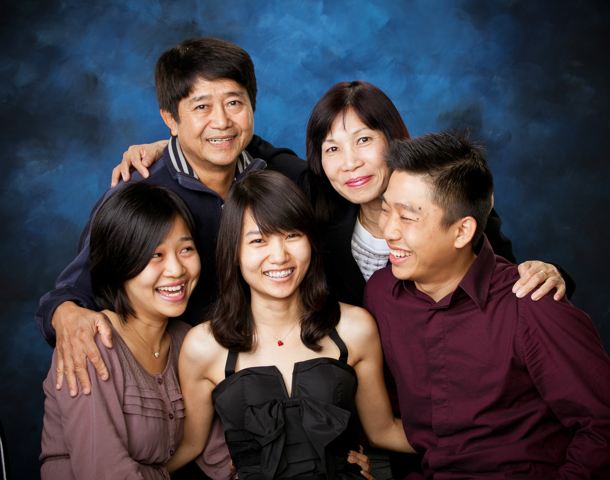 Five people posing together smiling in front of a blue studio backdrop.